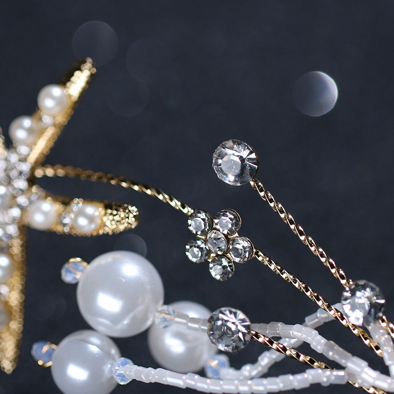 A close-up of the Seaside Starlight Pearl and Starfish Hairpiece, highlighting its detailed starfish motifs and elegant pearls on a dark background. 